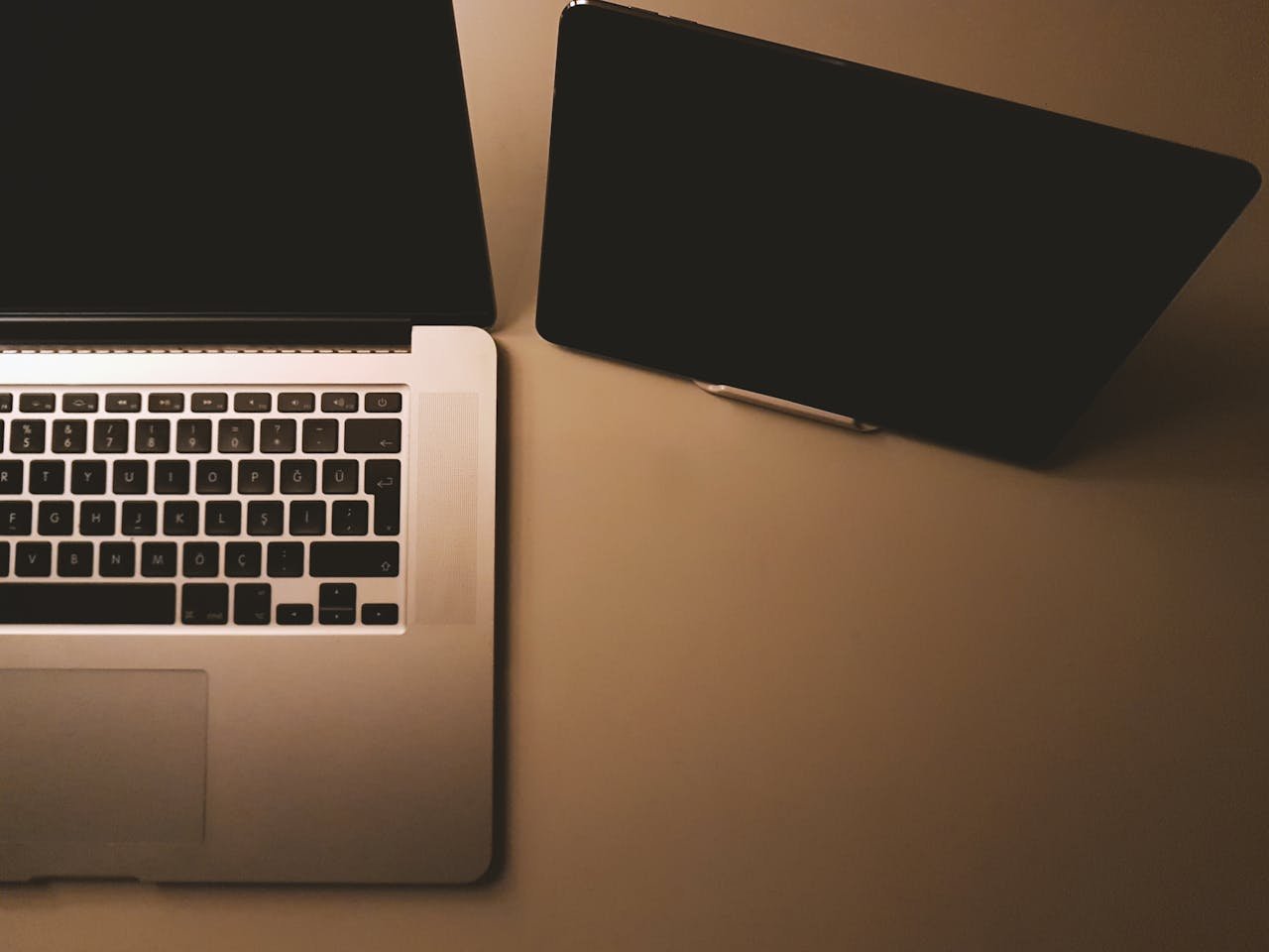 A minimalist workspace featuring a laptop and tablet in a dimly lit setting, ideal for tech themes.